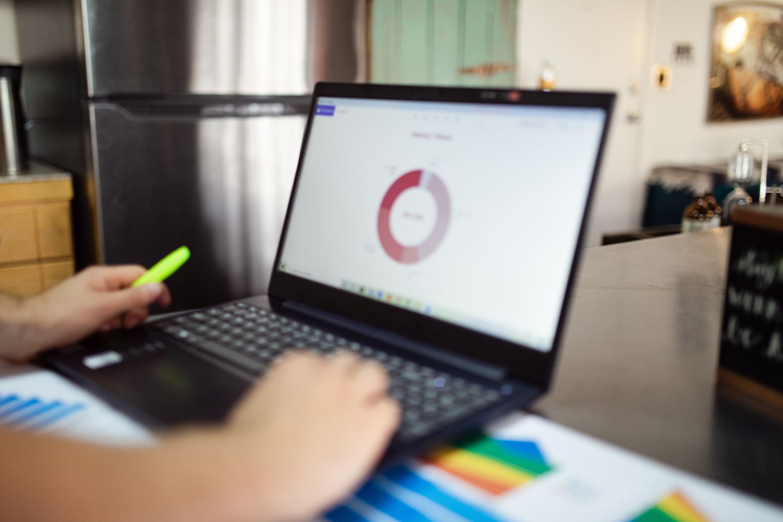 Analyst reviewing a dashboard and printed charts beside a laptop