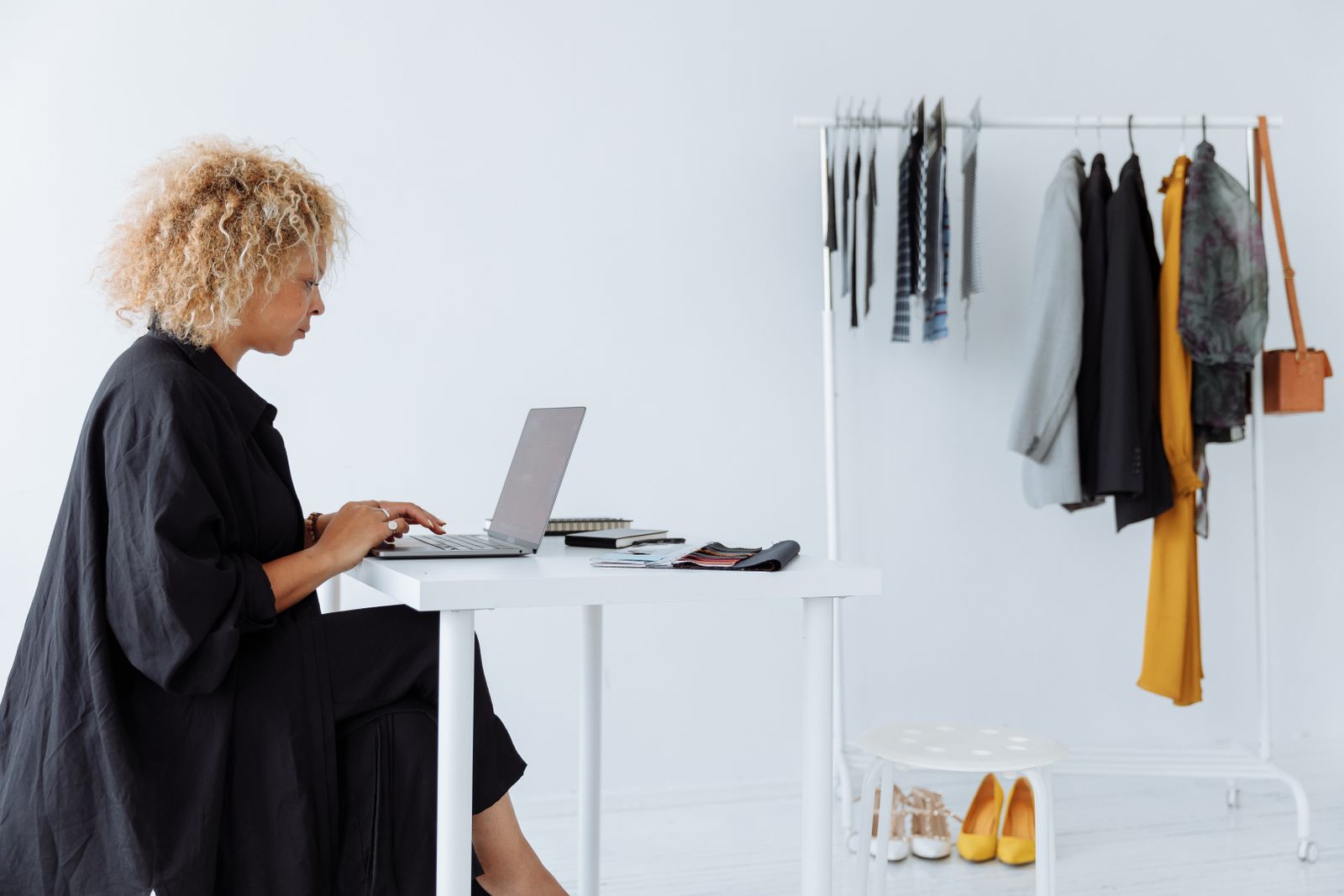 Clothing seller editing an eBay title beside a rack of apparel