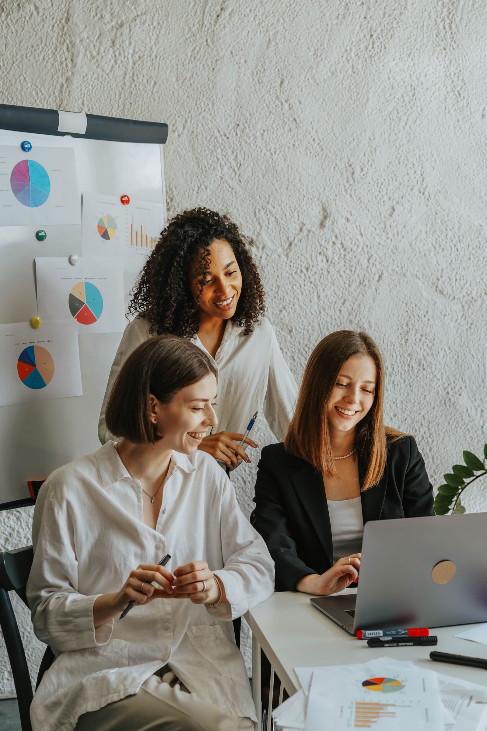 Three smiling colleagues reviewing listing data together in an office