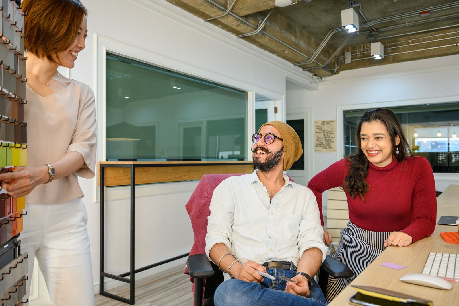 Three smiling colleagues discussing a repeatable clothing photography workflow in a bright office