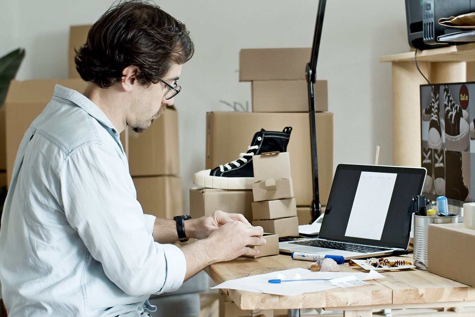 Ecommerce seller checking product details beside boxes and a laptop