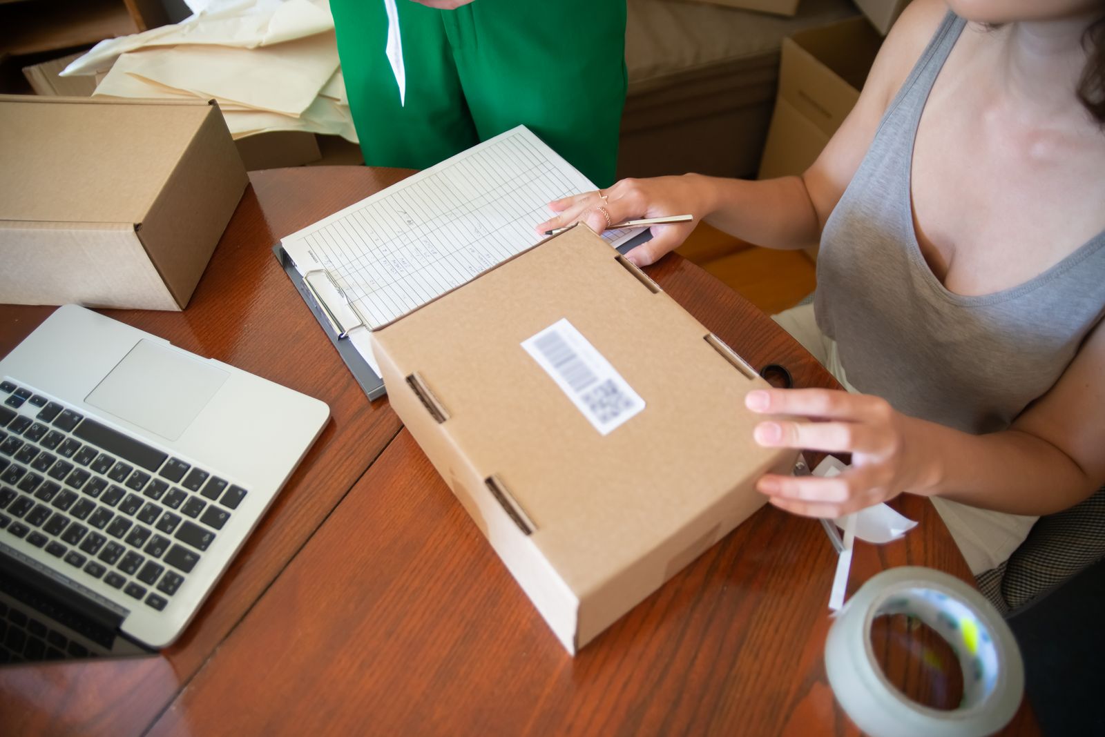 Two small-business operators packing online orders beside a laptop